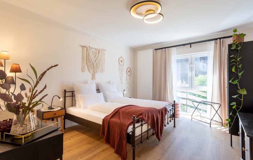 Helles Schlafzimmer mit zwei Betten, modernen Möbeln und einem großen Fenster zur Terrasse , Cozyhomes Ferienimmobilien, Ferienwohnung Bad Arolsen, Ferienhaus Kellerwald, Ferienhaus Edersee, Ferienwohnung Arolsen